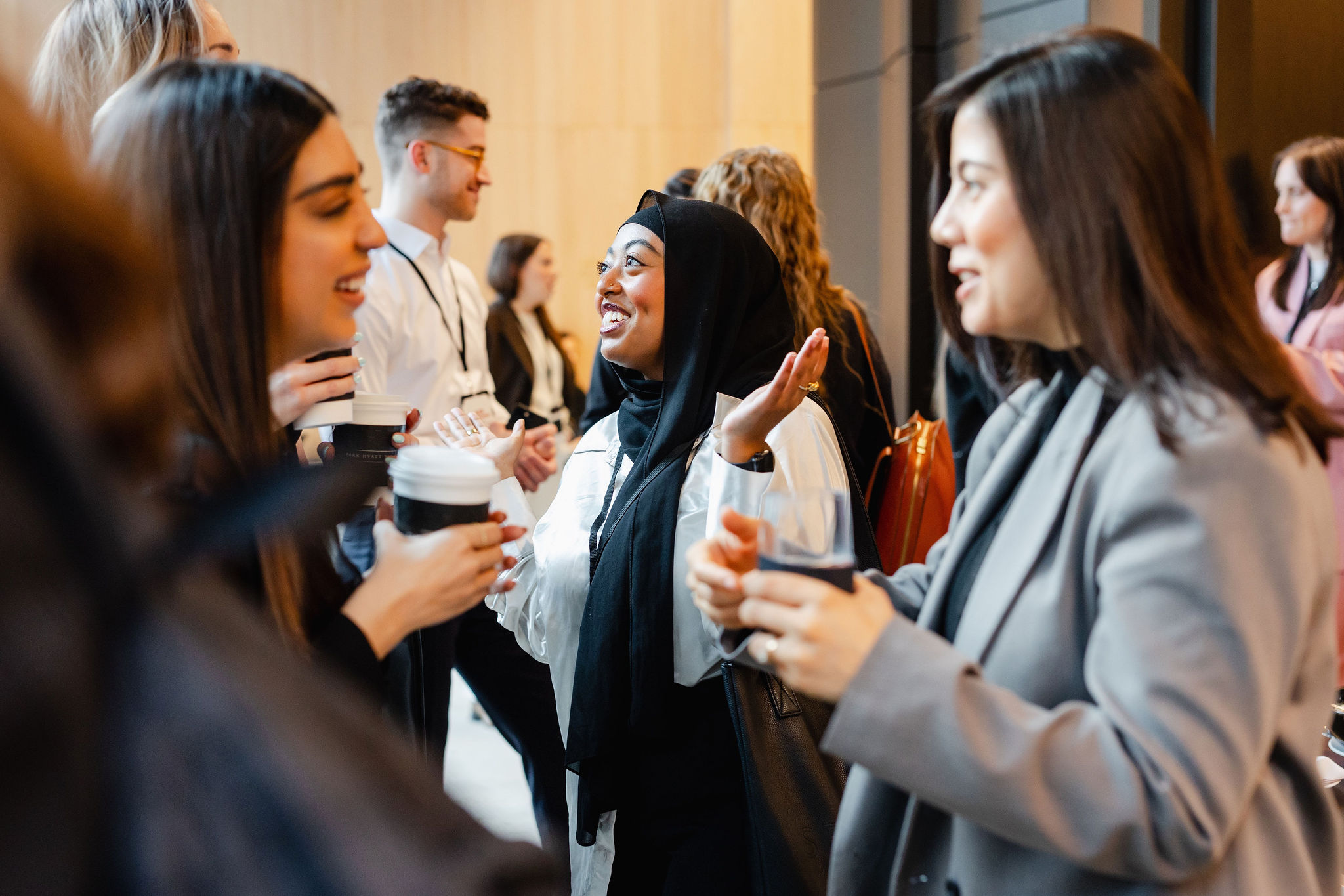 People are engaged in conversation, holding coffee cups amid the warmth of an indoor gathering, while moments are perfectly captured through brand photography.