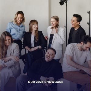 Seven people, casually dressed, sit and stand together indoors, smiling and laughing in a relaxed corporate photography setting. Studio lighting equipment is visible in the background. Text at the bottom reads "OUR 2025 SHOWCASE.