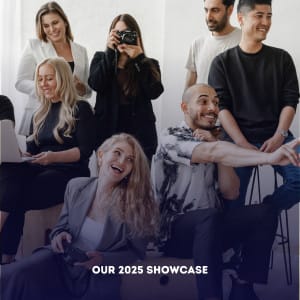 A group of seven people, some seated and some standing, interact and smile in a bright room, captured in a modern corporate photography style. Text at the bottom reads: "OUR 2025 SHOWCASE.